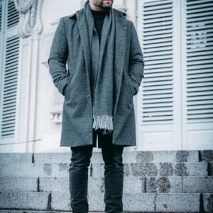 man in gray coat standing beside white wooden door